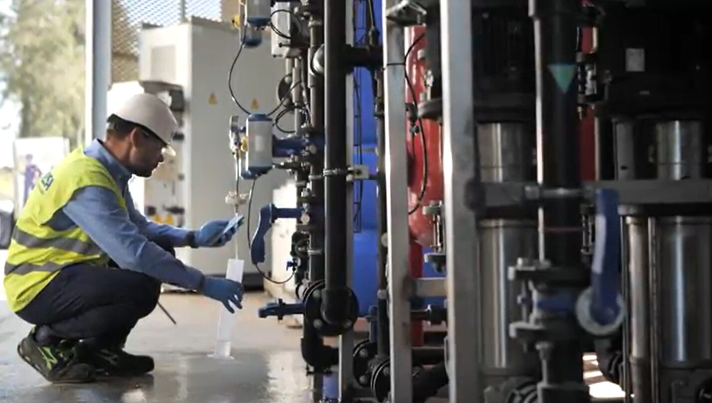 Técnico tomando una muestra de agua en una planta de tratamiento industrial